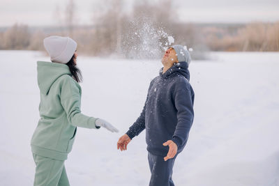 Happy couple playing winter game in forest outdoors. love and leisure concept.