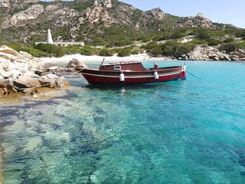 Boat moored on sea against mountain