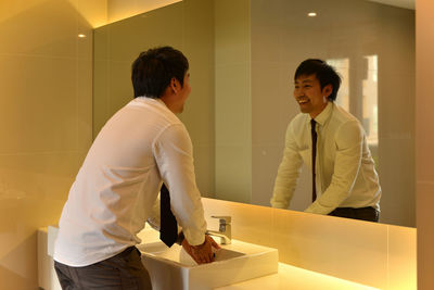 Smiling businessman washing hands in bathroom