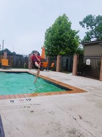 Man by swimming pool against sky