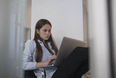 Young woman sitting at desk typing on her laptop.