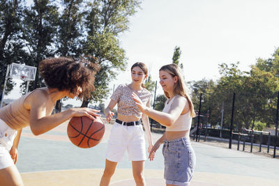 Portrait of smiling friends playing basketball at park