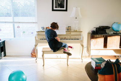 Teen girl sits on a piano bench inappropriately while playing piano