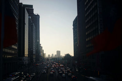 Traffic on city street amidst buildings against sky