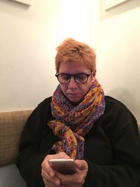 Mature woman using phone while sitting sofa