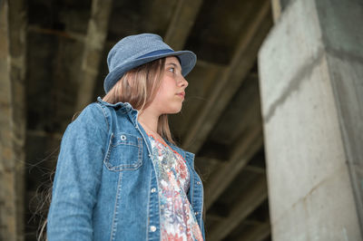 Young woman looking away while standing outdoors