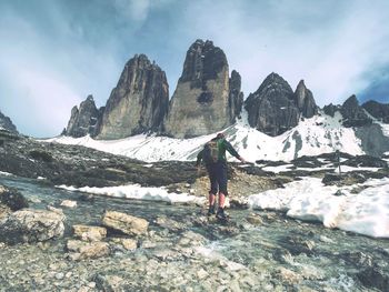 Rear view of man standing on mountain against sky