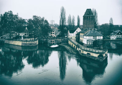 Bridge over river by buildings against sky