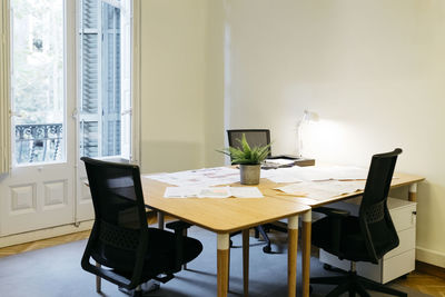 Empty chair arranged with papers over table at workplace