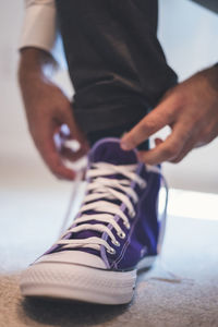 Low section of man tying shoelace on floor