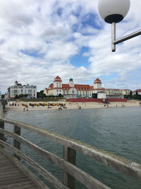 View of buildings by sea against cloudy sky