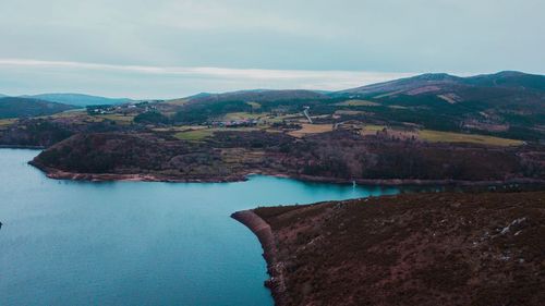 Scenic view of lake by mountains against sky