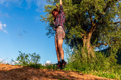 Full length of woman standing by tree against sky