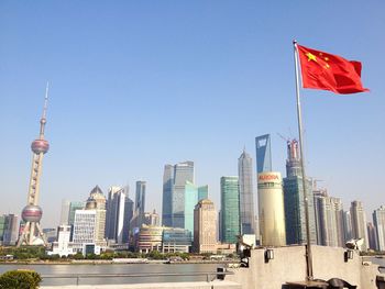 Chinese flag waving against oriental pearl tower and modern buildings in city