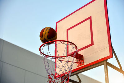 Basketball over hoop against clear sky