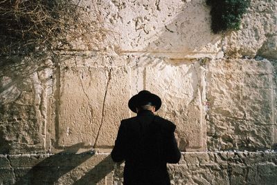 Rear view of woman standing against wall