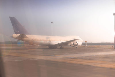 Side view of airplane on airport runway against sky