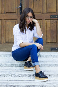 Young woman using mobile phone while sitting outdoors