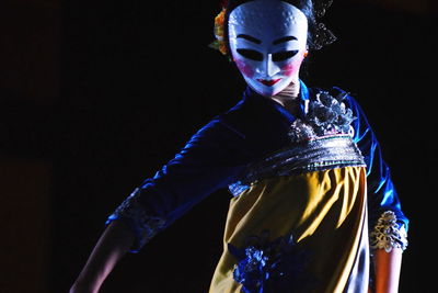 Woman wearing mask while dancing in darkroom