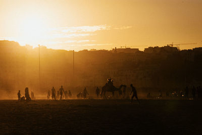 People on field against sky during sunset