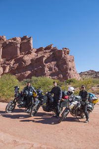 Group of friends standing beside touring motorbikes in desert