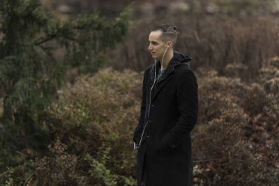 Side view of young man looking away in forest