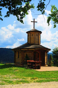 Church on field by building against sky