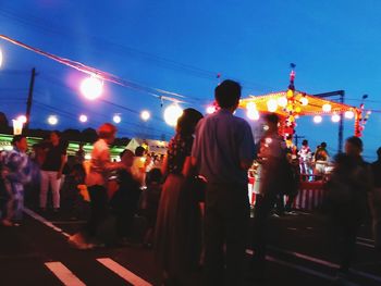 People at music concert against sky in city at night