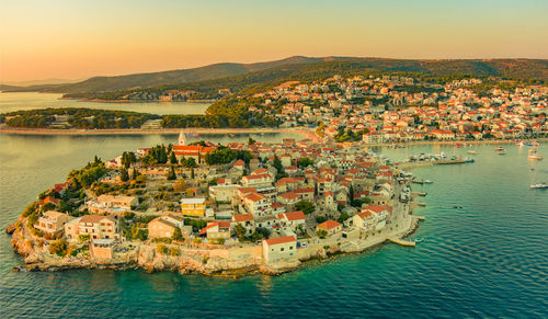 High angle view of townscape by sea against sky during sunset