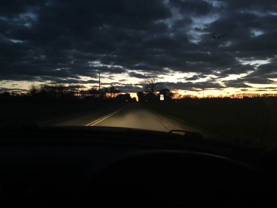 CAR ON ROAD AGAINST STORM CLOUDS