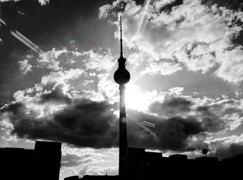 Low angle view of communications tower against cloudy sky