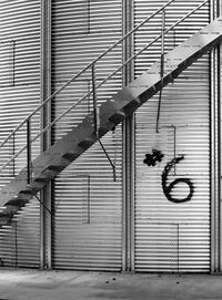 A metal stairway climbing up the side of a old large agricultural seed silo