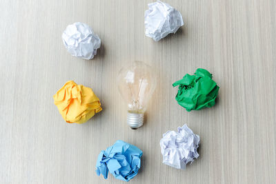 High angle view of light bulb amidst crumpled paper balls on table