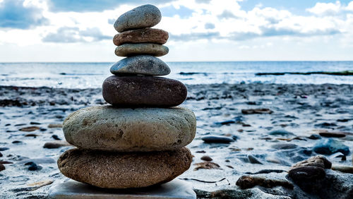 Stack of pebbles on beach against sky