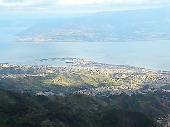 Aerial view of sea by mountain against sky