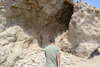 Rear view of man standing against rock formations