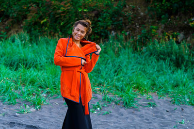 Portrait of smiling young woman standing by plants