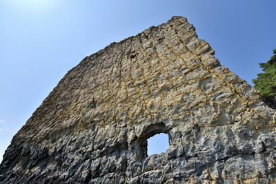 Low angle view of stone wall against clear blue sky