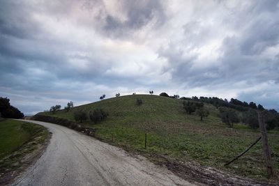Road amidst field against sky