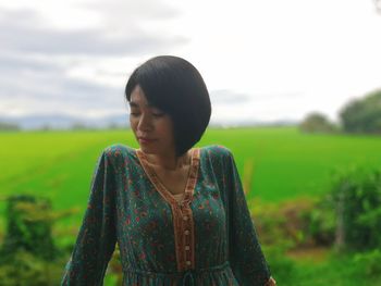 Thoughtful woman standing against field