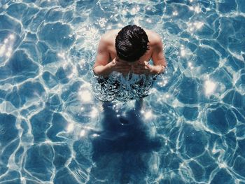 Shirtless man swimming in pool