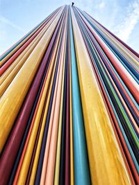 Low angle view of multi colored pencils in row against sky