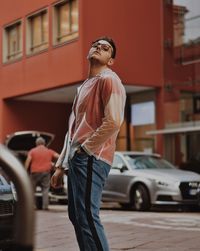 Full length of man standing by car in city