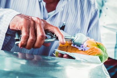 Cropped image of vender putting ice cream on bun