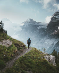 Rear view of man walking on mountain against sky