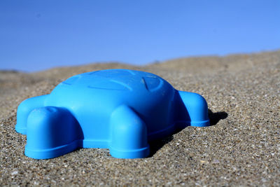 Close-up of sunglasses on beach against blue sky