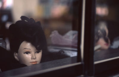 Mannequin seen through glass at clothing store