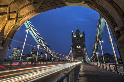 Light trails on bridge in city against sky