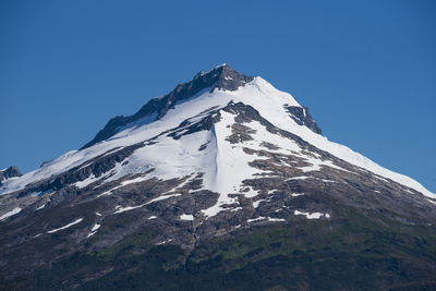 Low angle view of snowcapped mountain against clear blue sky