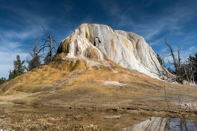 Low angle view of rock formation against blue sky during sunny day